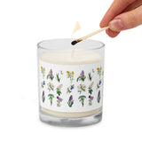 A person lighting a glass jar soy wax candle with Spring flowers design all around.