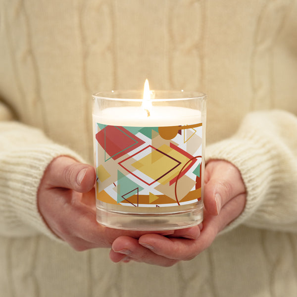 A lighted glass  jar candle being held by  two hands and decorated with a Southwest theme abstract illustration with geometric shapes and calming pastel colorscolors